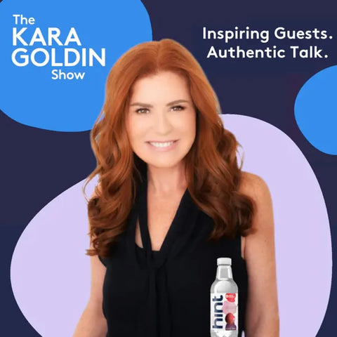 Promotional image for The Kara Goldin Show podcast. A smiling woman with long red hair, wearing a black sleeveless top, stands holding a bottle of Hint water. The background features abstract blue and purple shapes with text reading: 'The KARA GOLDIN Show' and 'Inspiring Guests. Authentic Talk.