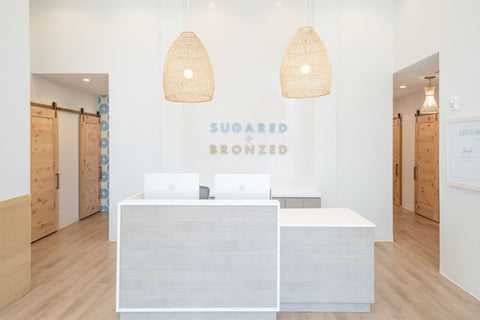 Modern interior with a reception desk and 'Sugared & Bronzed' branding.