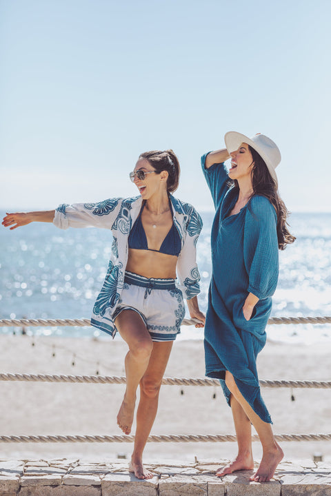 Two women in beach attire standing on a stone pathway with ocean view