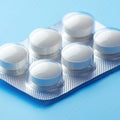 White pills in a blister pack on a light blue background