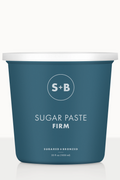 A blue tub labeled 'SUGAR PASTE FIRM' from Sugared and Bronzed, containing sugar paste for hair removal.