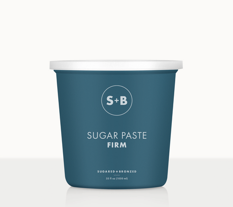 A blue tub labeled 'SUGAR PASTE FIRM' from Sugared and Bronzed, containing sugar paste for hair removal.