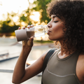 Woman drinking water outdoors with a blurred background