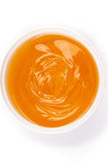 The top-down view of an open white plastic tub with the orange-colored sugar paste contained within in view