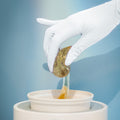 Sugaring paste being pulled from a tub by a white gloved hand